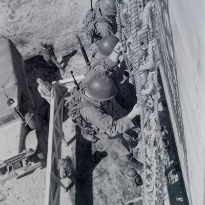 Soldiers practicing climbing down the side of a ship on cargo nets