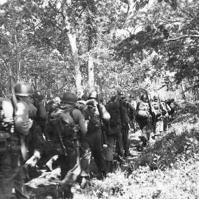 Soldiers on a road march in a wooded area