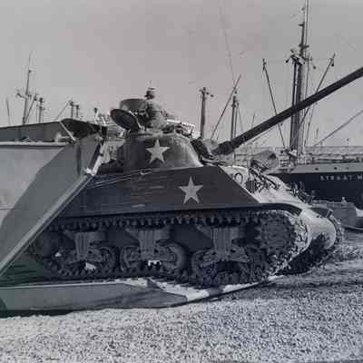 Tank driving off of a beach landing craft