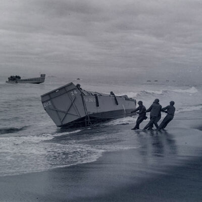 Soldiers hauling a landing craft onto the beach