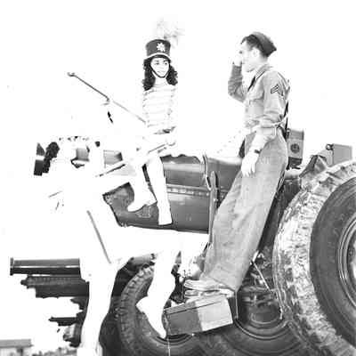 Majorettes and a soldier posing on an artillery piece