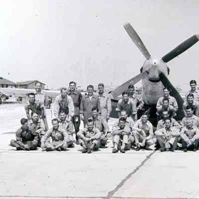 Group posing in front of P-51