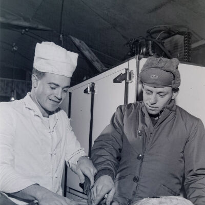 Cook and a soldier preparing food in a kitchen