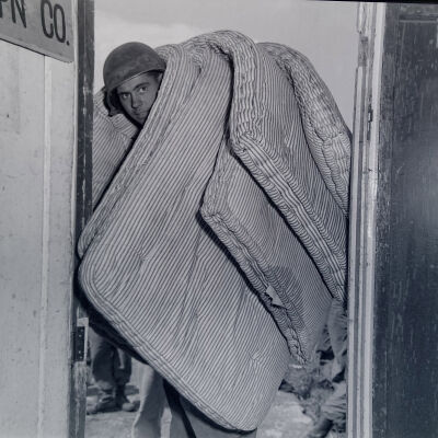 Soldier carrying mattresses into barracks