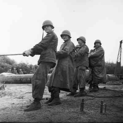 Soldiers pulling on rope in rain gear