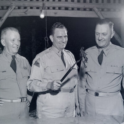 General Styron and soldiers admiring a piece of barbecued chicken