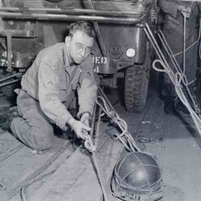 Soldier securing cargo ropes for a Jeep inside a cargo aircraft