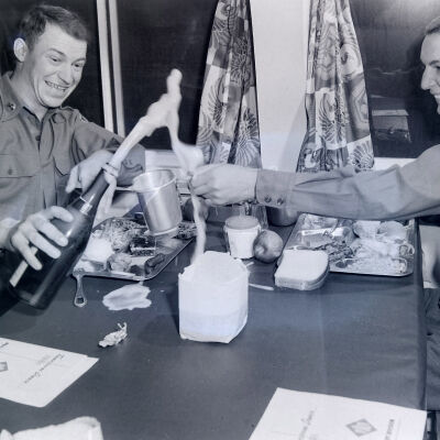 Two soldiers drinking champagne in a mess hall