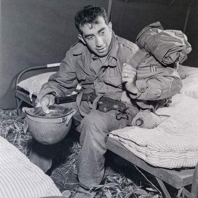 Soldier in field gear sitting on a cot in a tent