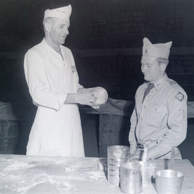 Soldier watching a cook prepare bread