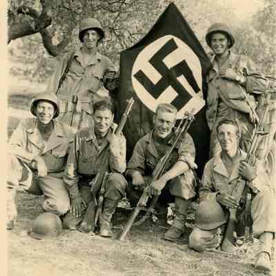 Soldiers posing with captured Nazi flag