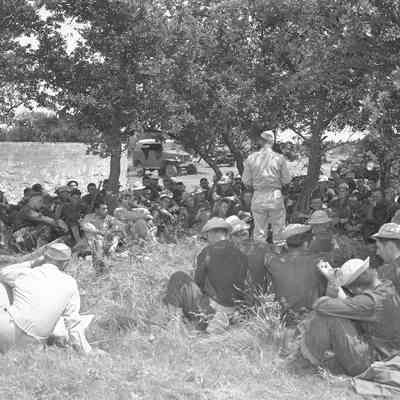 Soldiers sitting and listening to an officer