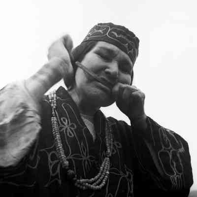 Ainu woman in traditional dress playing a musical instrument