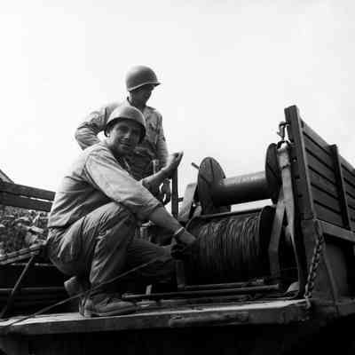 Soldiers stringing commo wire from back of truck