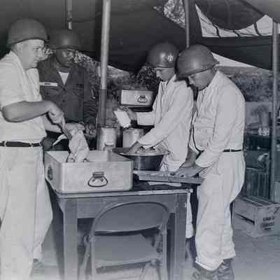 Group of cooks and a soldier working in a field kitchen