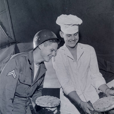 Soldier helping a cook bake pies