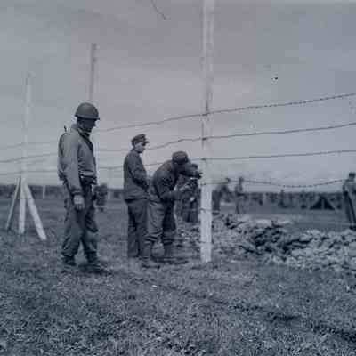Soldiers and German prisoners working on a fence