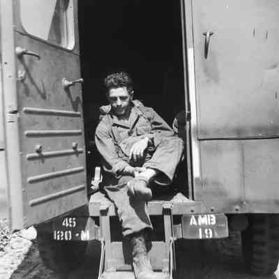 Soldier examining his foot while sitting in an ambulance