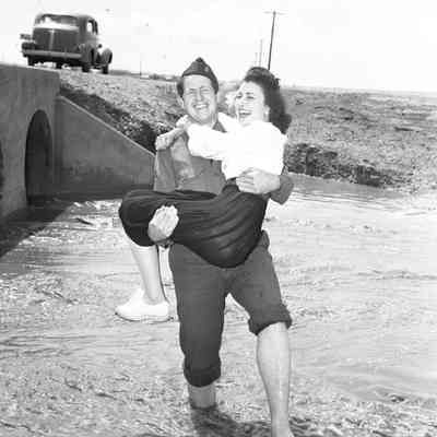 Soldier carrying a girl across a flooded drainage ditch