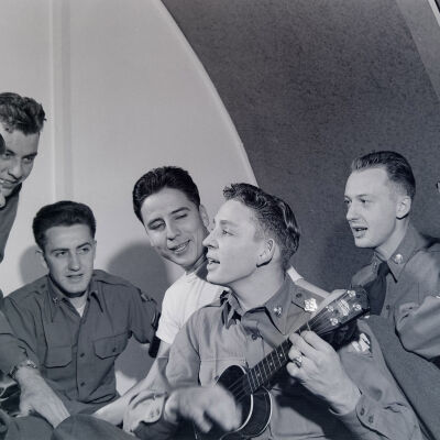 Group of soldiers singing with a ukulele player