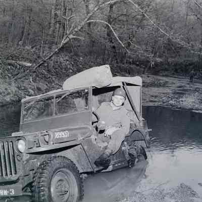 Soldier sitting in a jeep stuck in a hole
