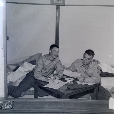 Two soldiers writing letters in a Japanese hotel room