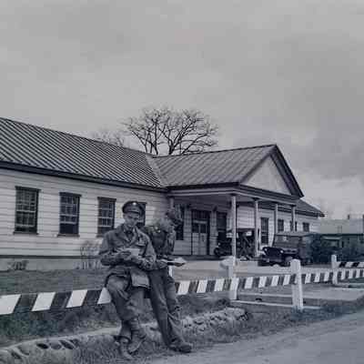 Two soldiers reading their mail in front of the Camp Crawford post office