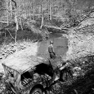 Soldier with jeep parked next to a stream