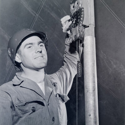 Soldier hanging a cuckoo clock on a tent pole