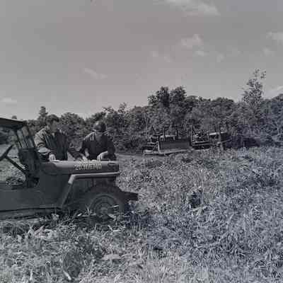 Soldiers examining plans with bulldozers in the background