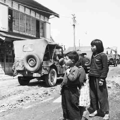 Japanese children watching jeep convoy