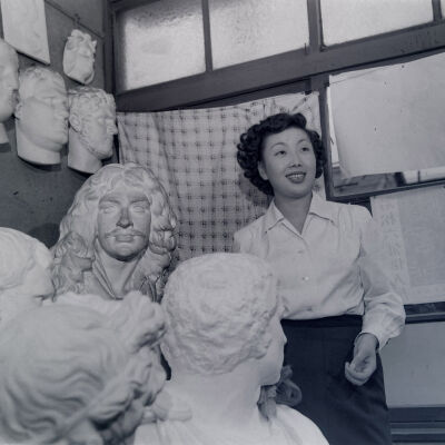 Japanese woman in a studio filled with plaster busts