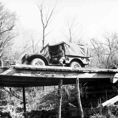 Soldier guiding a truck over wooden bridge