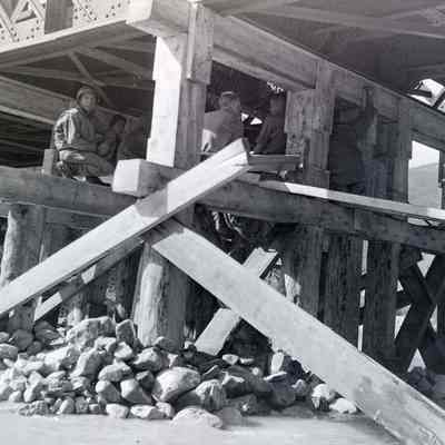 Soldiers sitting under Bailey bridge