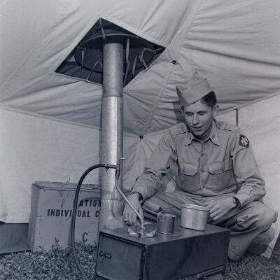 Soldier heating up rations on tent stove