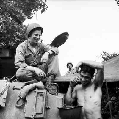 Soldier shaving using his steel pot for a basin