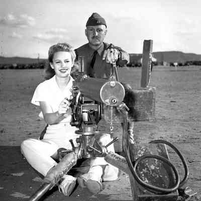Woman sitting behind a water cooled machine gun