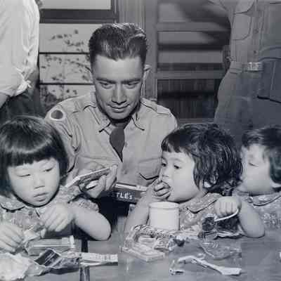 Soldier giving candy to three Japanese children