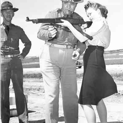 Soldier showing woman how to shoot a rifle