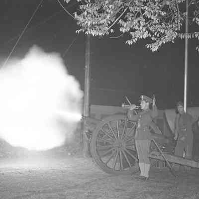 Solider playing the bugle while a cannon is fired in the background