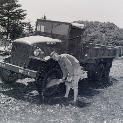 Soldier washing is 2 1/2-ton truck in a stream