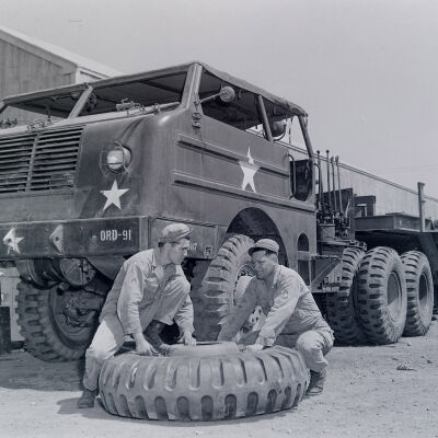 Soldiers changing tire on tank-hauling tractor
