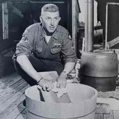 Soldier using a scrub board and tub in his tent