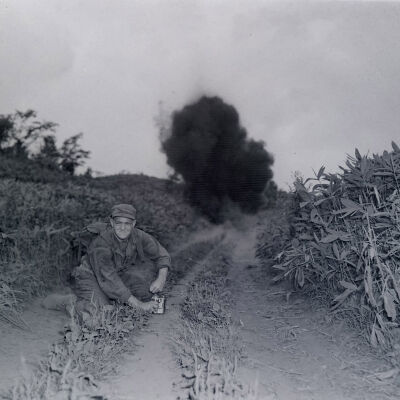 Soldier setting off an explosive charge in a field