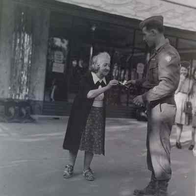 Soldier giving a cigarette to elderly woman