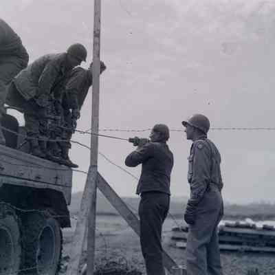 Soldiers and German prisoners working on a fence