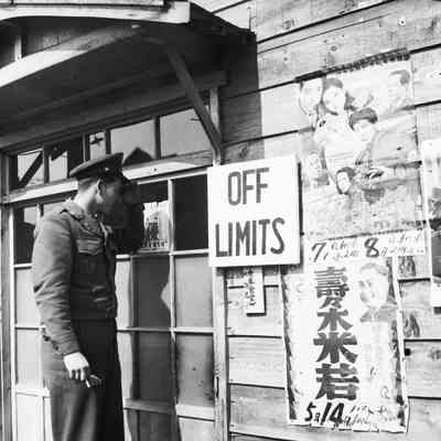 Soldier looking in the window of a building posted "Off Limits"