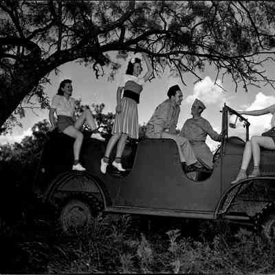 Girls and soldiers sitting on a command car