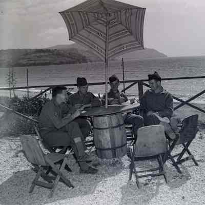 Soldiers resting under umbrella on the beach