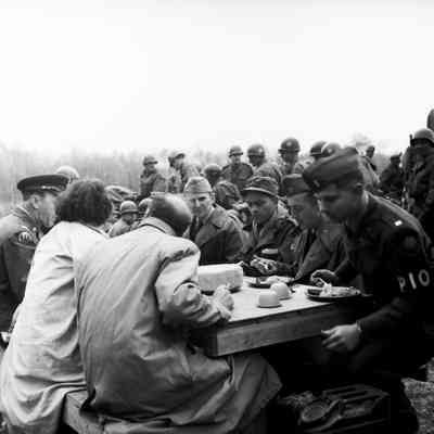 Press Information Officer eating outdoors with a large group of soldiers and civilians